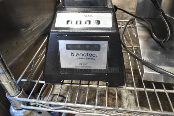 Blendtec ES3 countertop blender on metal shelf, featuring control buttons and commercial labeling, showing minor wear.