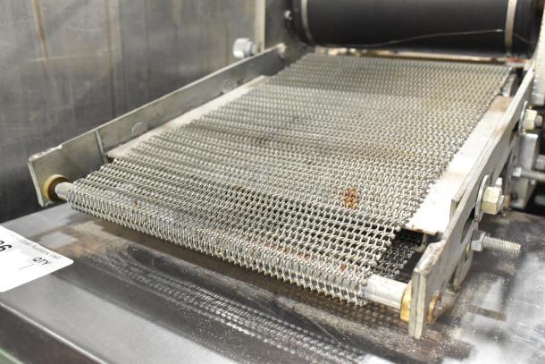 Lenin MQ077 automatic tortilla machine, metal build, in used condition, showing conveyor detail, on commercial casters.