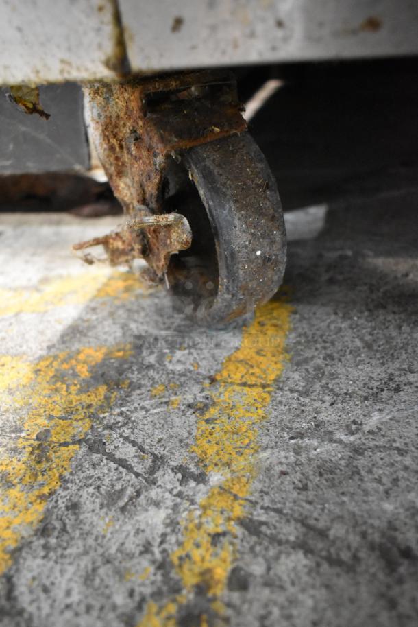 Rusted commercial caster wheel of Continental 1R-HD stainless steel reach-in cooler, indicating wear and use.