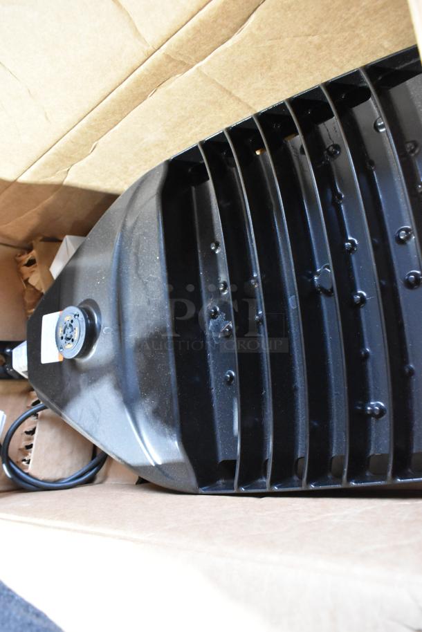 9 Current Evolve LED Series Area Lights in box, black color, vented design. New condition with labels visible.