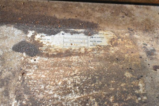 Close-up of a weathered label on a Baxter stainless steel commercial natural gas mini rotating rack oven. Serial details visible.