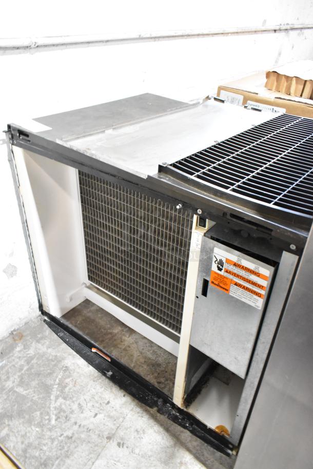 Manitowoc Stainless Steel Commercial Ice Head, sturdy design, visible warning labels, excellent condition, ideal for businesses.