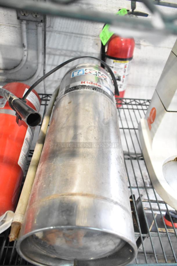Four fire extinguishers, including a Kiddie model, on a metal shelf. Visible wear; local pickup only.