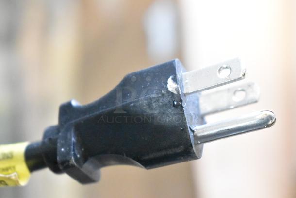 Close-up of a three-prong plug for the Bunn CDBCF15-APS coffee machine, showing minor wear on the metal prongs.