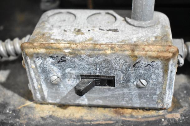 Rusted metal electrical box with on-off switch and conduit connections, showing wear and exposure.