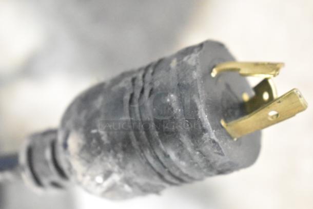 A close-up of a metal plug, showing wear and two brass prongs.
