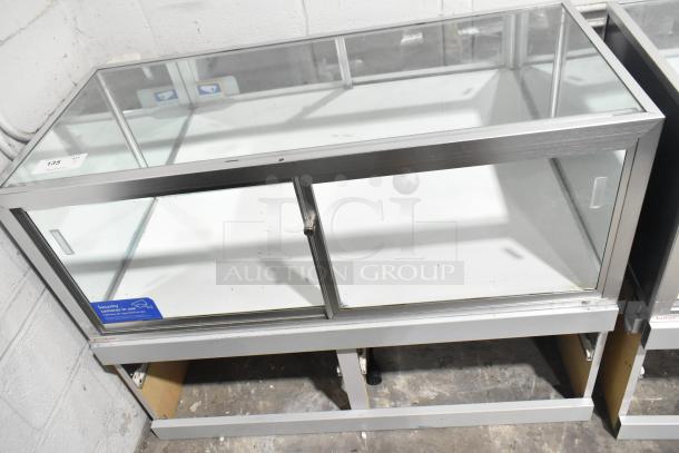 Jahabow metal commercial dry merchandise display case, glass panels, silver frame, excellent condition, security label visible.