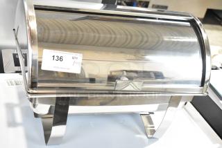 Stainless steel roll top chafer with curved lid, reflective finish, and sturdy legs. Visible label reads "136."