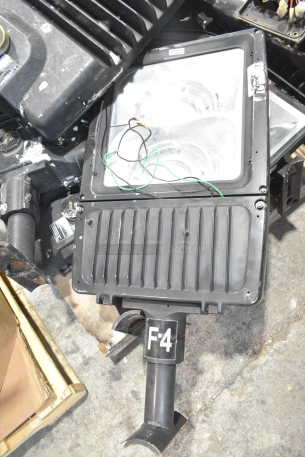 11 metal outdoor light fixtures, including GE, in fair condition. F4 marking visible, mixed wiring present. Auction lot.