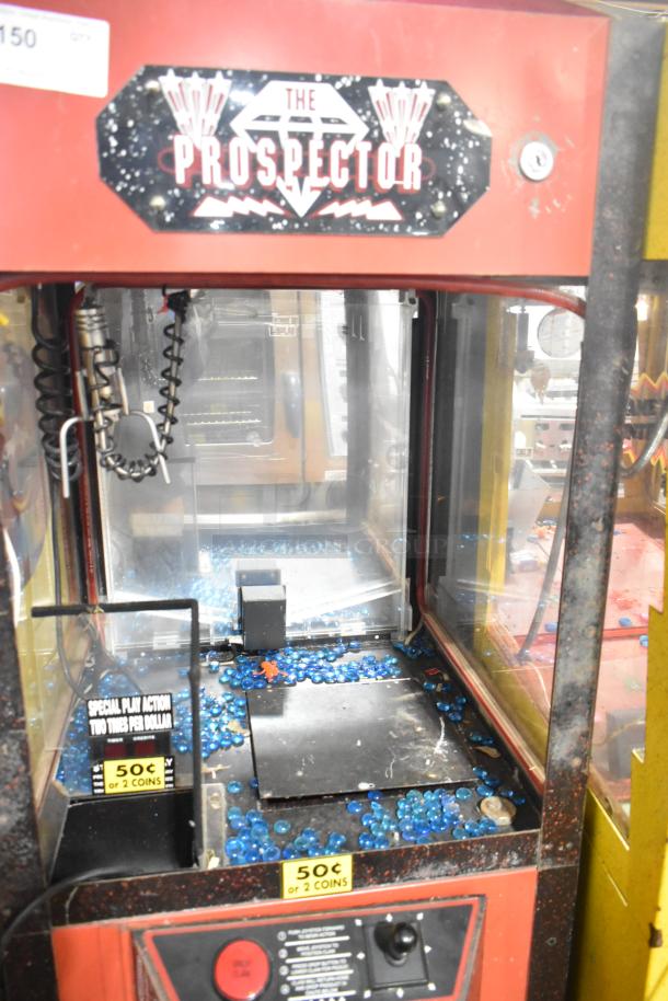 The Prospector metal claw machine game, red exterior, coin slots marked 50¢, 120 volts, 1 phase; filled with blue spheres.