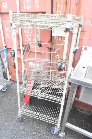 Tan 3-tier wire shelving unit with two extra shelves and commercial casters. Tags show marked numbers. Buyer to dismantle.