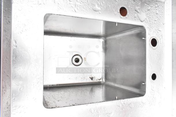 Stainless steel commercial single bay sink with backsplash, under shelf, and drainage. Appears in good condition.