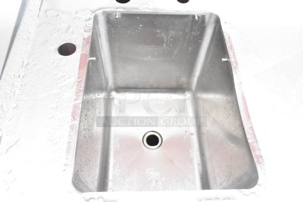 Stainless steel commercial single bay sink with backsplash and under shelf, showing light use and clean surface.