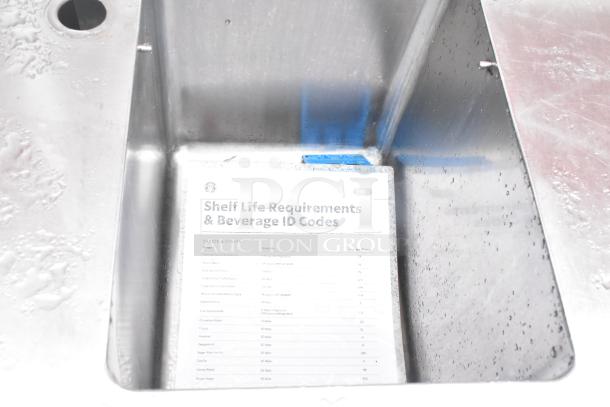 Stainless steel commercial single bay sink with integrated backsplash and under shelf. Slight water marks visible.