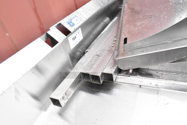Stainless steel commercial single bay sink with backsplash, under shelf, and visible water droplets, showing moderate use.