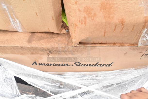 Cardboard box labeled "American Standard," showing signs of water damage and wear, wrapped in plastic.