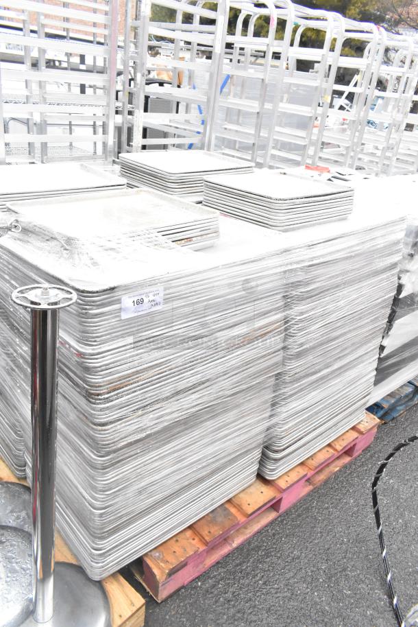 Stack of 392 metal baking pans including full and half sizes, 18x26x1, 13x18x1, on pallets. Auction tag visible.