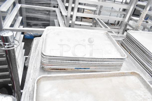 392 metal baking pans, full and half size, visible stacking. Sizes 18x26x1 and 13x18x1 inches. Slightly used.