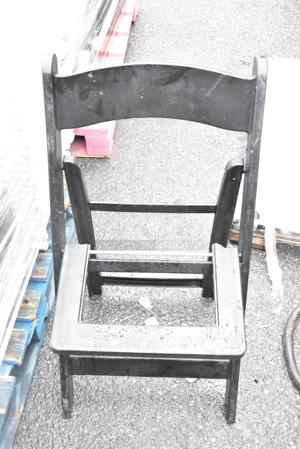 52 black folding chair frames in good condition on a pallet, auction includes white folding chairs.