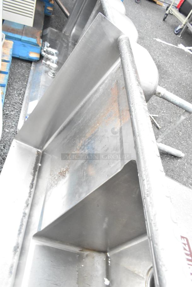 Stainless steel 3-bay sink with dual drain boards, missing one leg, showing signs of rust.