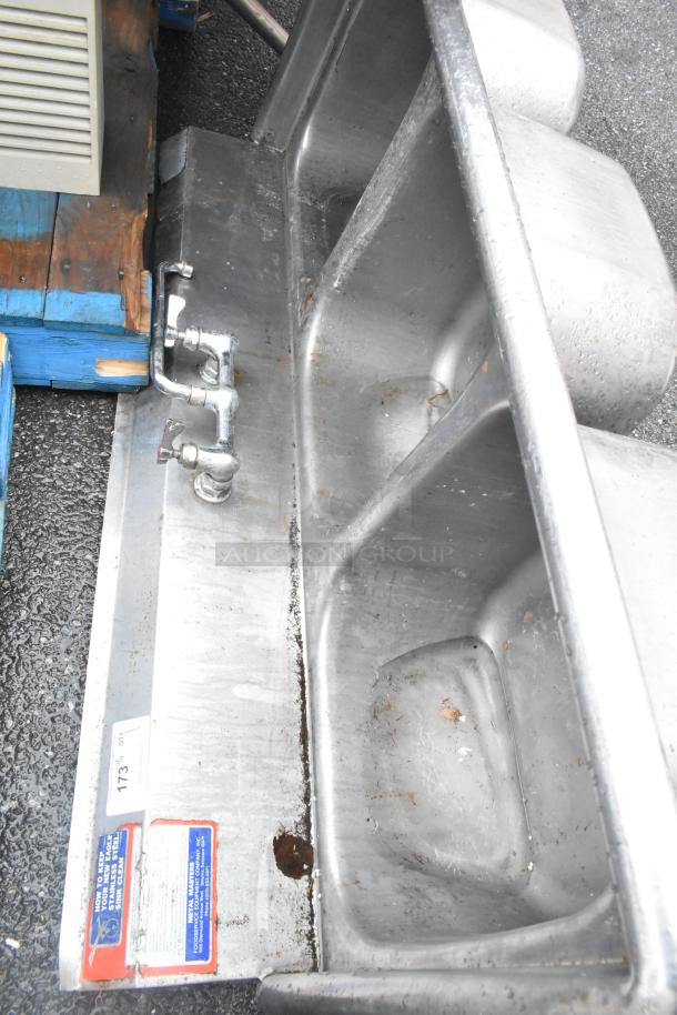 Stainless steel 3 bay sink, missing right legs, visible rust and wear, faucet included, cleaning instructions label present.