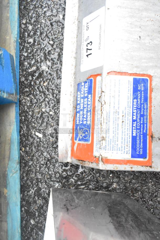 Stainless steel 3 bay sink with missing right legs. Features usage wear. Labels indicate cleaning instructions and manufacturer details.