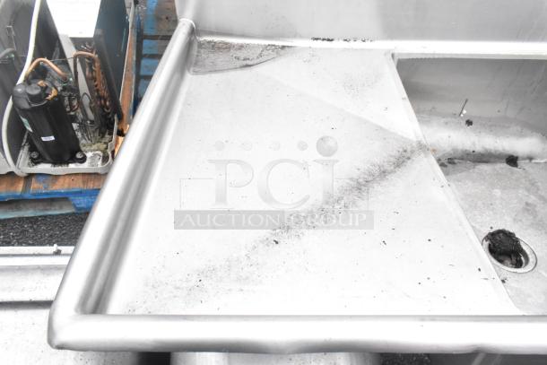 Stainless steel 3 bay sink with dual drain boards in used condition. Some dirt visible on surface. No tags or markings seen.