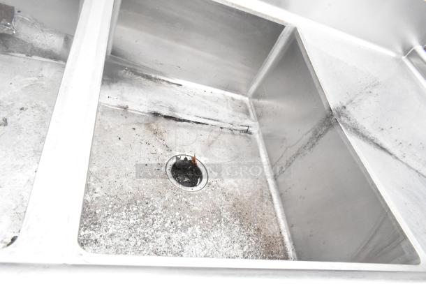 Stainless steel 3 bay sink with dual drain boards, visible wear and stains, suitable for commercial use.