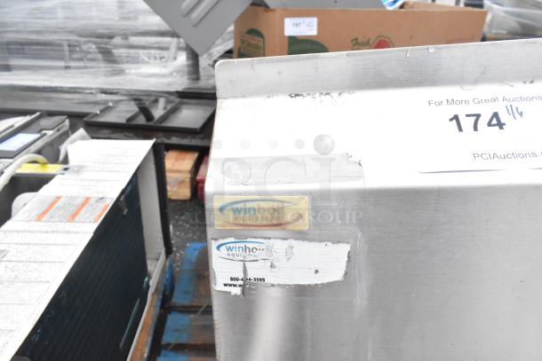 Stainless steel 3 bay sink with dual drain boards, brand Winholt. Visible labels and markings. Good condition.