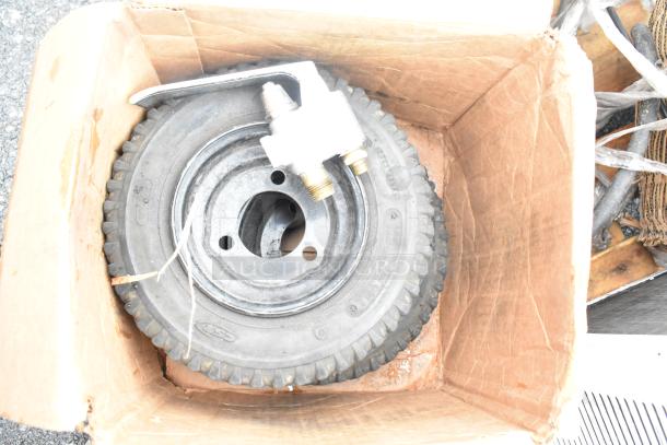 Cardboard box containing a tire with a metal valve attachment. Box appears used and frayed.