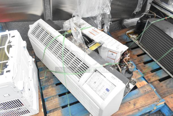 Metal air conditioner, horizontal unit on pallet, visible vents, control panel, aged appearance, secured with straps.