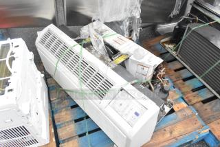 Metal air conditioner, horizontal unit on pallet, visible vents, control panel, aged appearance, secured with straps.