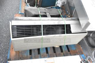 Metal air conditioner unit on wooden pallet, horizontal vents, some surface wear, secured with green straps, labeled "178."