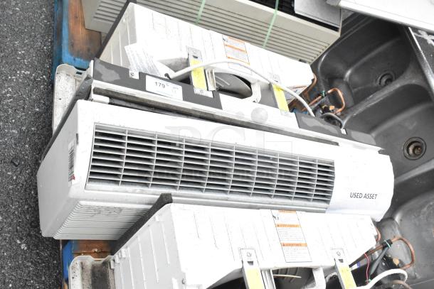 Two used metal air conditioners, visible tags indicating “Used Asset” and stock number “179% QTY X2”, on display.