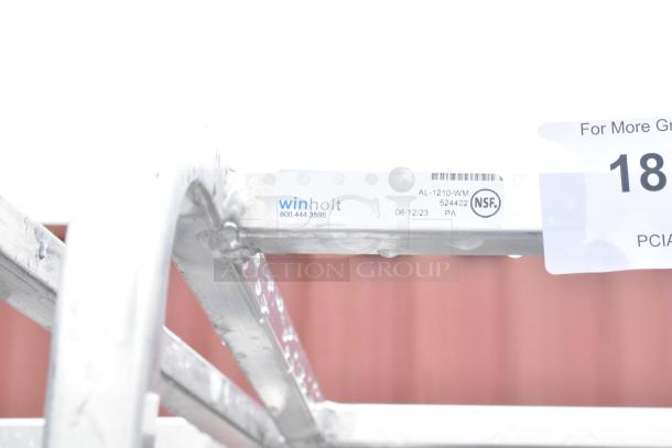 Winholt metal commercial pan transport rack with label showing model AL-1210-WM, on casters, visibly sturdy and well-maintained.