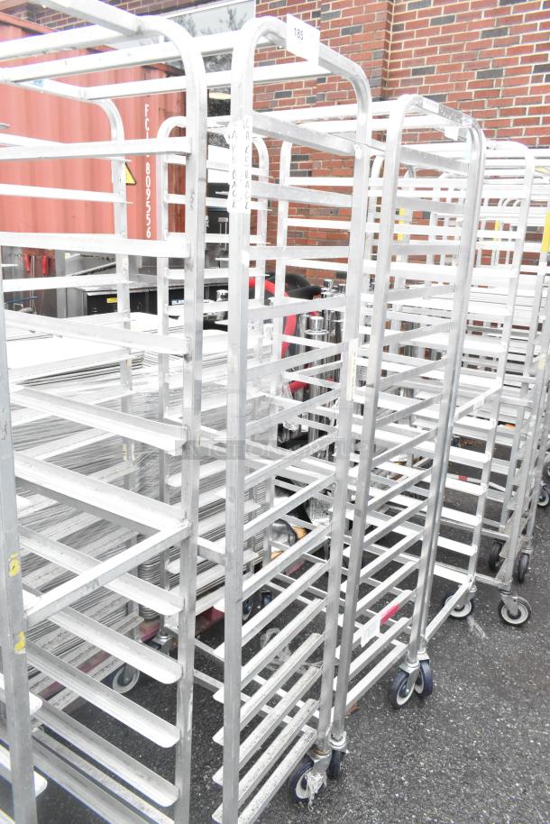 Two Winholt metal commercial pan transport racks on casters, used, durable construction. Tags indicate "CAKE RACK."