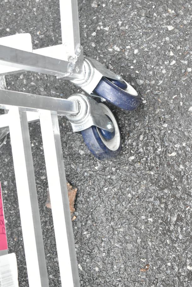 Winholt metal commercial pan transport rack on commercial casters, condition appears used, visible blue wheels.