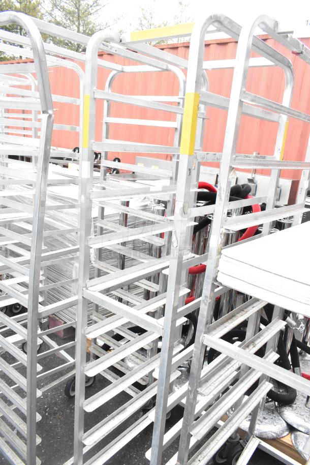 Two Winholt metal commercial pan transport racks with commercial casters, used condition, visible yellow labels.