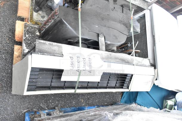 Two used metal air conditioners with visible wear, cords attached, placed on pallets. Labels read "Used Assets."