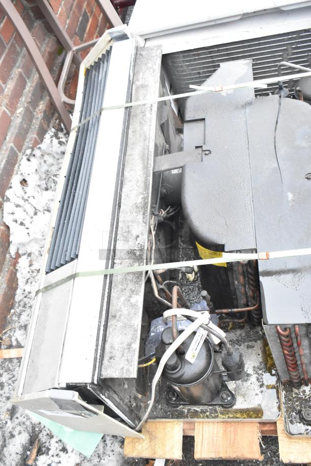 Two metal air conditioners on a wooden pallet, showing exposed wiring and parts. Used condition, sold as a pair.