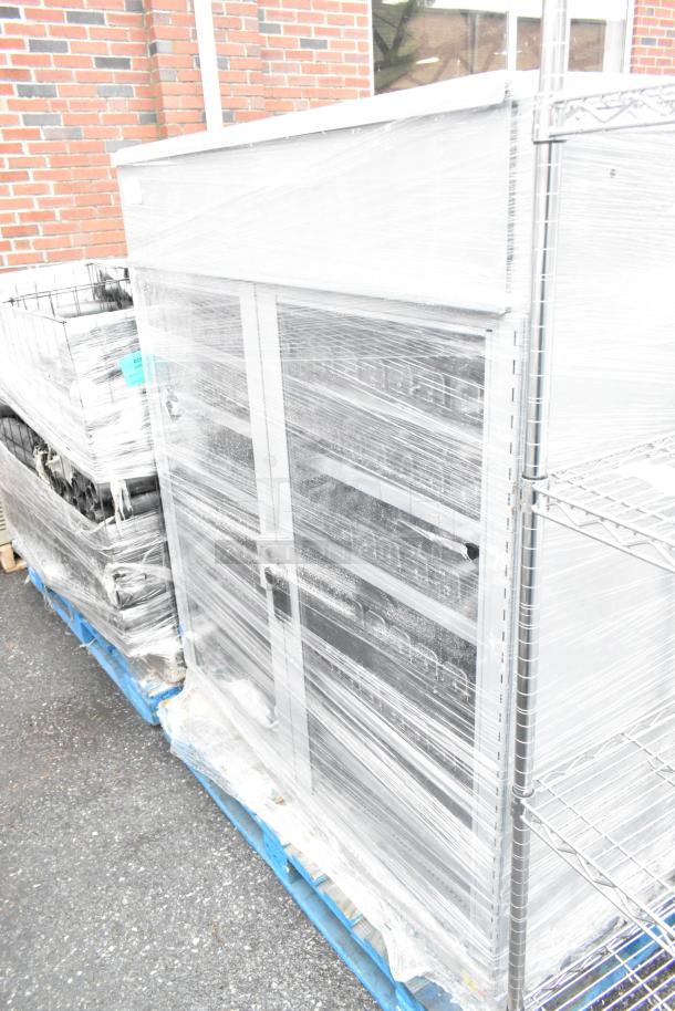 Two gray, two-door merchandising cabinets wrapped for protection, in good condition, ready for auction.