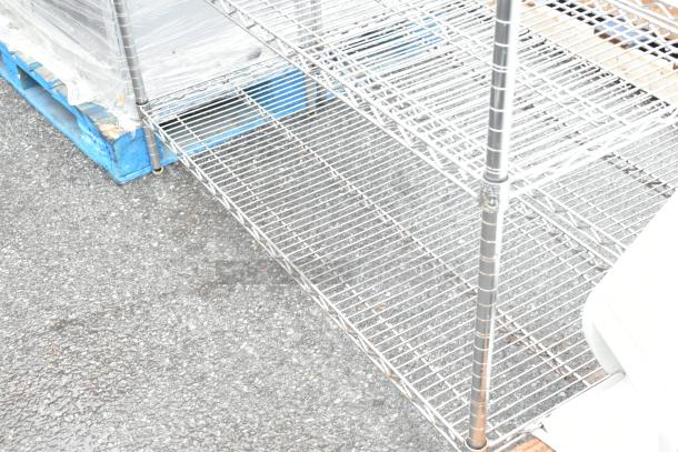 Chrome finish 5-tier wire shelving unit, undismantled, on pallets. Durable metal construction, ideal for storage. Buyer dismantles.