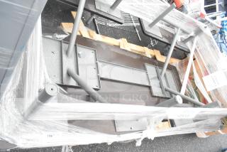 Industrial-style metal table, assembled, upside down for packaging. Sturdy legs, wrapped for protection. Appears new.