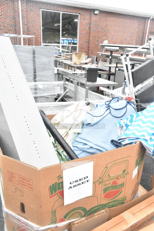 Pallet lot with patio umbrellas and locker, used condition. Box marked "USED ASSET" with mixed items including cloth and metal parts.