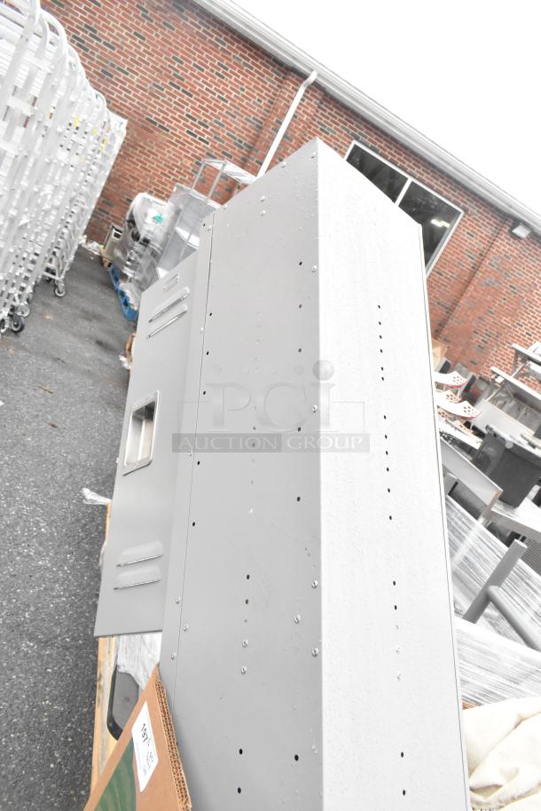 Pallet lot with grey metal locker, patio umbrellas, and various items. Locker features vented doors and handles; overall used condition.