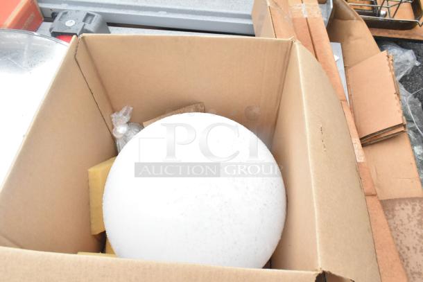 Pallet lot with a cardboard box containing a large white sphere and various gray items, including a round chrome finish unit.