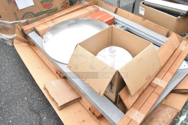 Pallet lot with various items including gray pieces, a chrome finish round unit, and cardboard boxes. Condition appears mixed.
