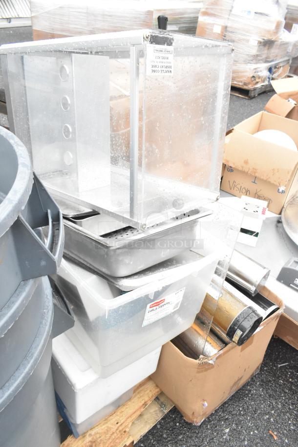 Pallet lot with poly gray trash cans, trash lids, folding table, and various containers. Visible labels indicate condition.