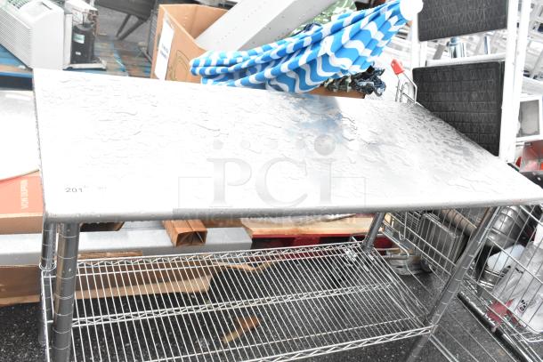 Stainless steel table with a chrome finish wire under shelf, watermarked surface, used condition.