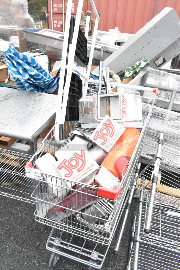 Chrome finish shopping cart filled with Joy ice cream cone dispensers and miscellaneous items; visible wear; labeled shelf number 002.
